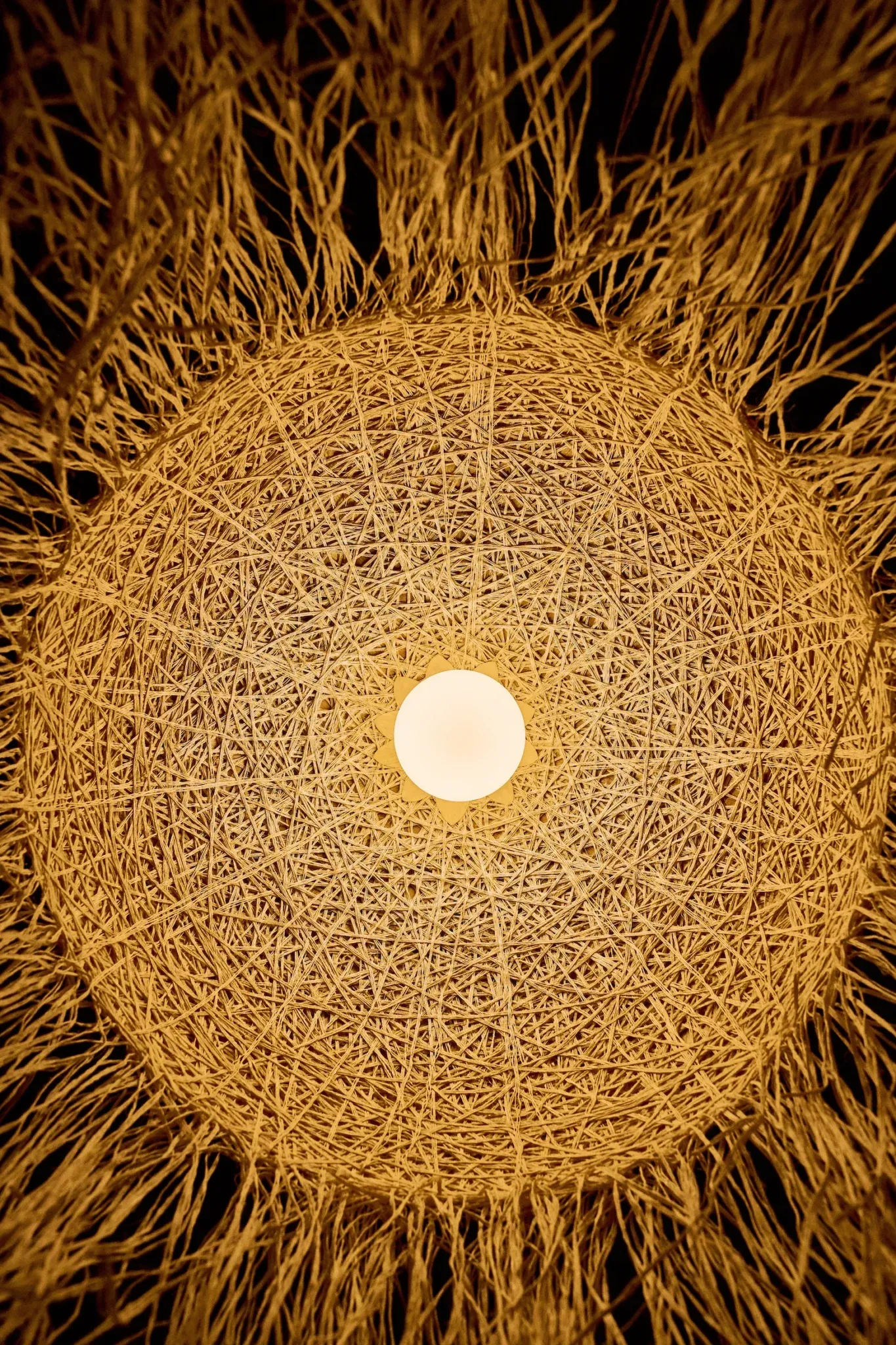 A woven pendant lamp glowing over the dining room