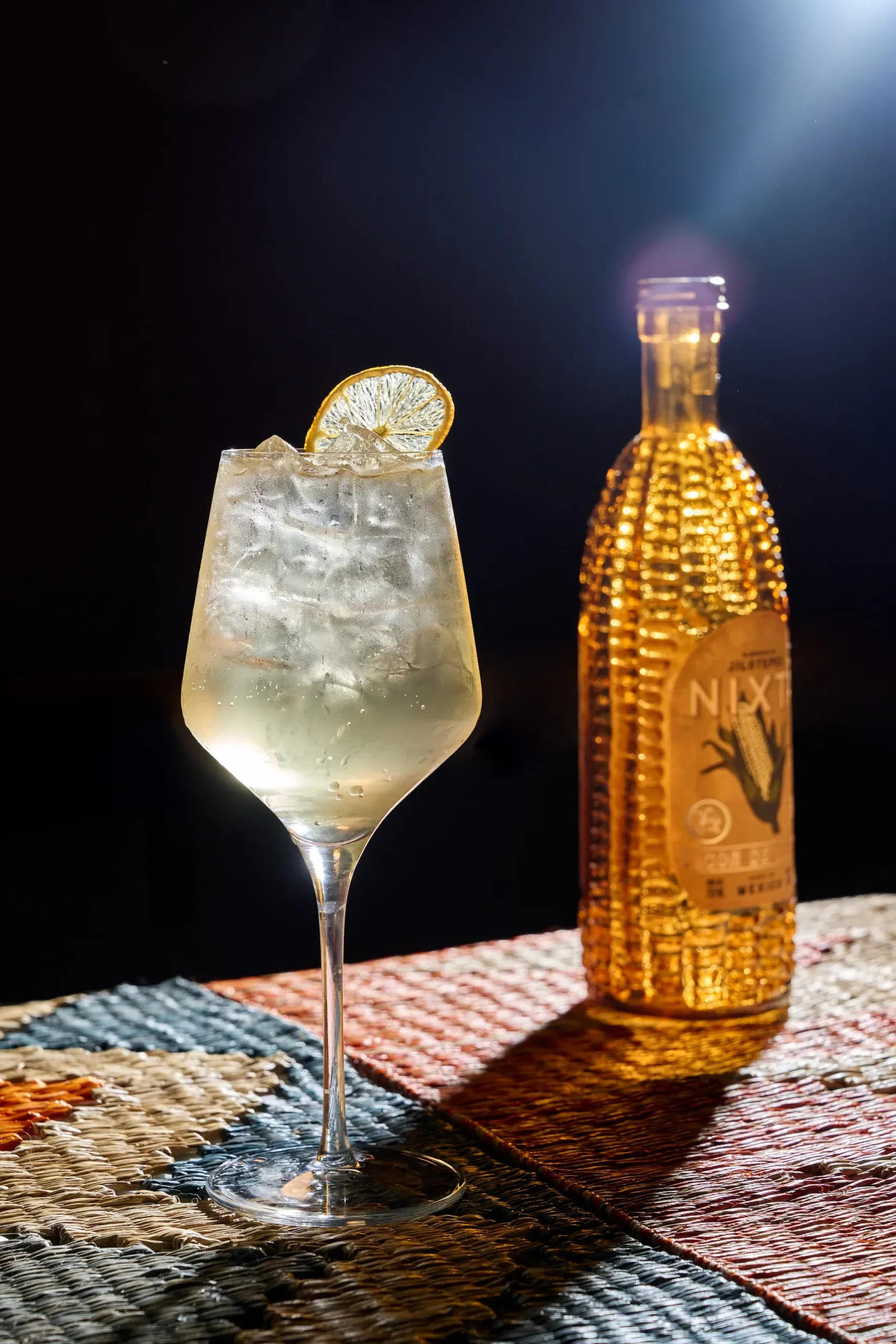 A spritz beside a bottle of Nixta corn liqueur